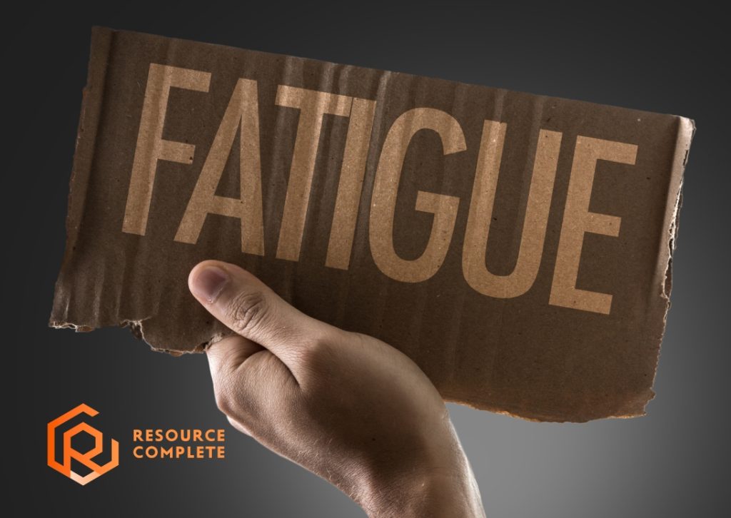 Hand holding a cardboard sign reading “FATIGUE,” Resource Complete logo in corner.